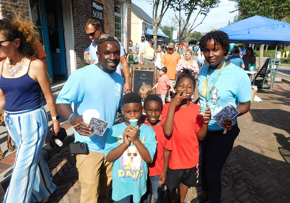 A family enjoys frozen treats on a downtown sidewalk during the festival