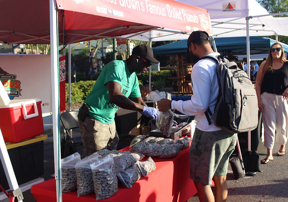 A vendor bags boiled peanuts for a customer at a Third Thursday booth